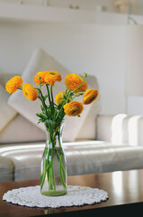 Bouquet of yellow flowers, ranunculus in a vase on a table in a cozy home on a sunny day in bedroom