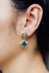 Woman wearing earrings made of colored gemstones looks luxurious.