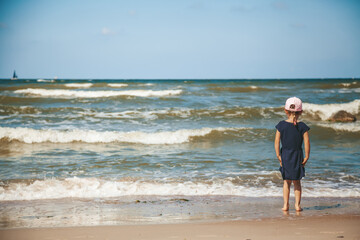 Little girl standing alone on the beach of a Baltic sea