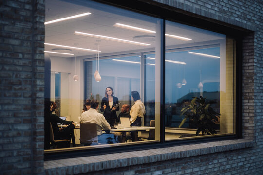 Mature businesswoman discussing with male and female colleagues in meeting at office
