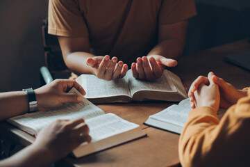 Christians and Bible study concept.Christian family sitting around a wooden table with open bible...