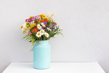 Bouquet of bright flowers in tin can vase on white table. Template for postcard. Concept Women's...