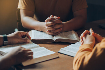 Christians and Bible study concept.Christian family sitting around a wooden table with open bible...