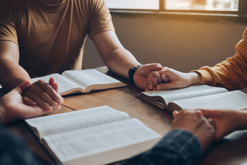 Christian family holding hands praying worship believe and seeking the blessings of God, fellowship, or bible study concept. They were reading the Bible and sharing the gospel. - obrazy, fototapety, plakaty
