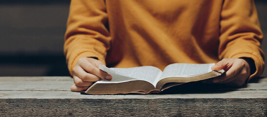 Christian woman wearing a yellow shirt reading and studying the bible at home or Sunday...