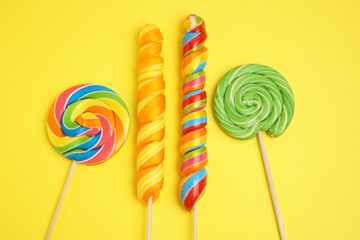 Four multi-colored lollipops on a yellow background.