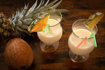 top view of pina colada glass on wooden background with coconut and pineapple - obrazy, fototapety, plakaty