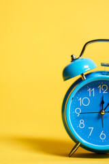detail of retro blue alarm clock on yellow background