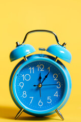 Retro alarm clock blue on yellow background with vertical photograph