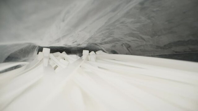 White nylon cable ties in a bag. Dolly slider extreme close-up. Laowa Probe