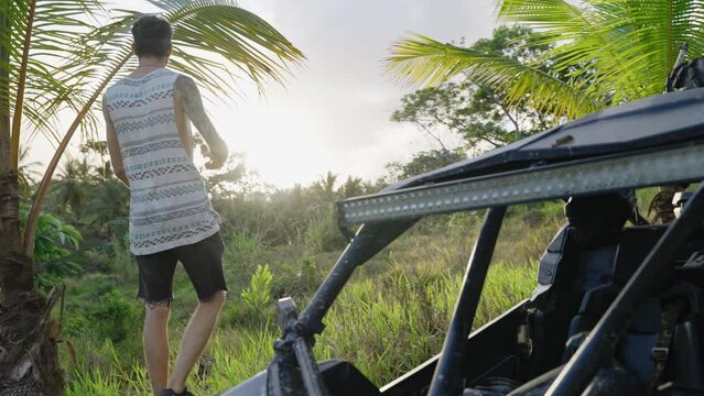 Dolly Shot Of Male Walking Past Parked Dirt Buggy To View Sunset At Punta Cana. Slow Motion
