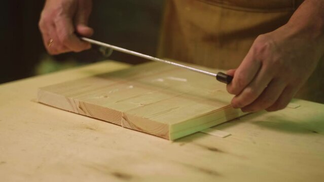 A mature carpenter makes works in his carpentry workshop, glues together wooden blanks