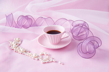 Obraz na płótnie Canvas ピンクのコーヒーカップと紫のリボンと真珠（ピンクバック）