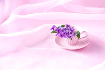 ピンクのコーヒーカップのスミレの花束