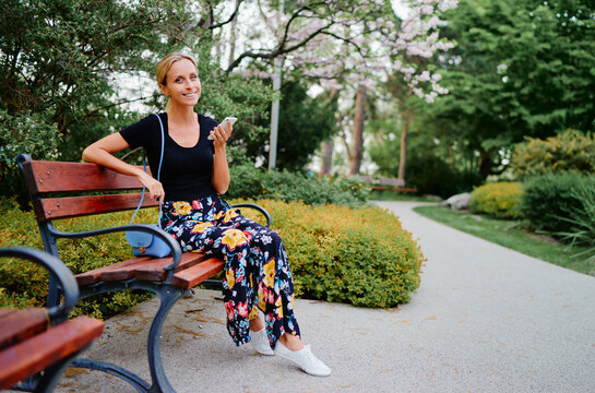 Attractive young woman using smartphone while sitting at the city park.