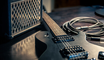 Close-up, black electric guitar on a dark background.