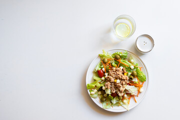  Tuna salad with lettuce, tomatos, carrot, corn  on white background with  glass water  and pepper...