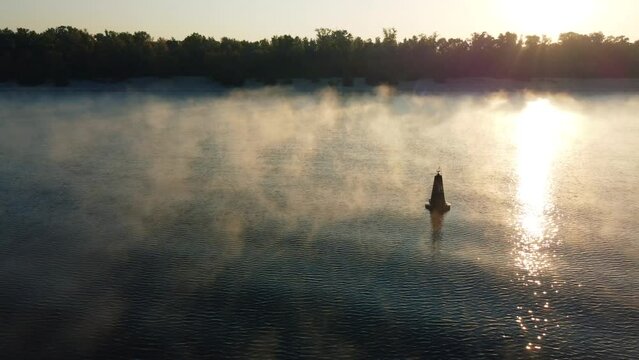 drone flies around a buoy on the river, morning mist over the water, fog