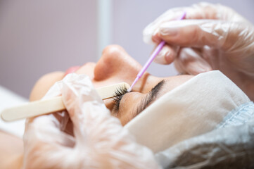The master cleans the eyelashes of a woman preparing before lamination. 