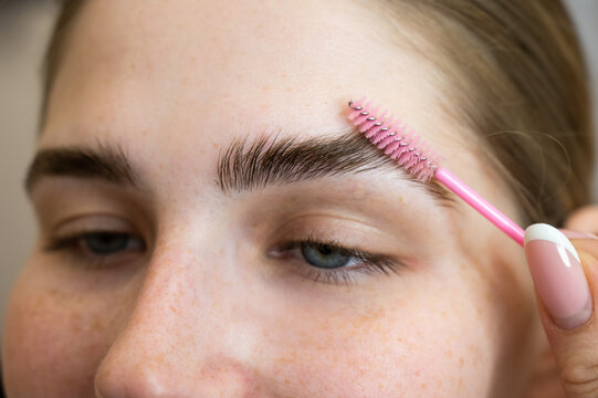 The master combs the eyebrows of the client after lamination of the eyebrows. 