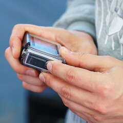 A man holds in his hands and looks through the footage on an action camera
