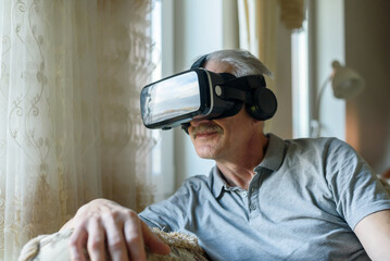 Senior man using VR glasses at home