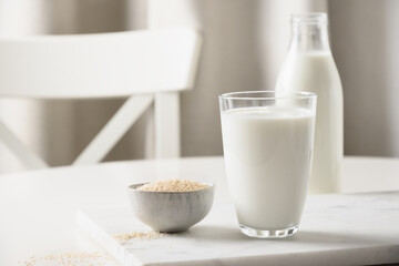 Fototapeta na wymiar Sesame milk and sesame seeds in bowl on white kitchen background. Lactose free. Close up. Lack of cholesterol. vitamins, amino acids, fiber, minerals