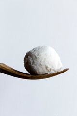 Coconut ice cream scoop on wood spoon.