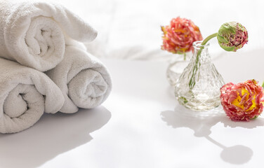 Close-up, white terry bath towels and flowers.