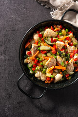 Chicken stir fry and vegetables on black stone. Top view