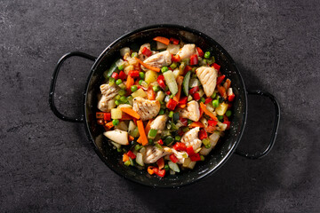 Chicken stir fry and vegetables on black stone. Top view