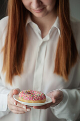 girl in a white shirt holds a saucer in her hands with a fresh tasty appetizing donut