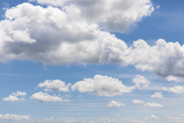 Naklejka na ściany i meble White clouds on blue sky background, cumulus clouds high on pale azure sky, beautiful aerial cloudscape view