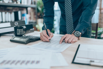 Accountant writing, checking and working on company data, document, report and calculator to calculate  on desk office. Accounting business concept.