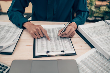 Investors working on desk office and using a pan and pointing to check tracking cost, balance, projit and  currency. Accounting and  Financial concept.