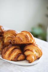Homebaked croissants on white plate on the table.