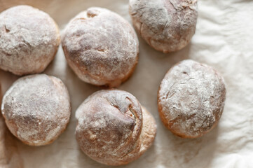 Fresh baked wheat-rye buns on baking paper, top view.