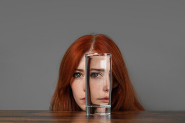 distorted face of woman looking through glass of water