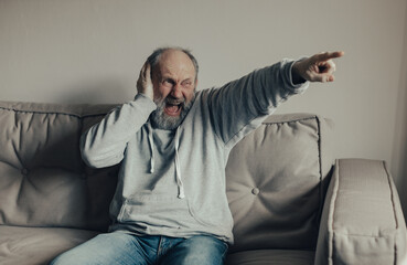Fototapeta premium Ukrainian frightened gray-haired man saw the explosion through the window. The husband is frightened by the sounds of war outside the window. Stop the war. Pray for Ukraine.