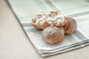 Fresh baked wheat-rye rolls on a cotton napkin on a table.