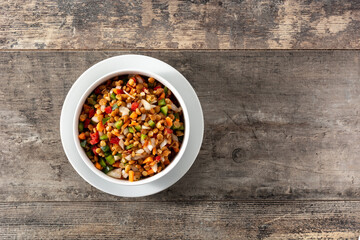 Lentil salad with peppers,onion and carrot in bowl on wooden table. Top view. Copy space