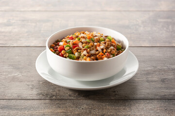 Lentil salad with peppers,onion and carrot in bowl on wooden table