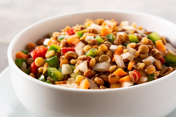 Lentil salad with peppers,onion and carrot in bowl on wooden table. Close up