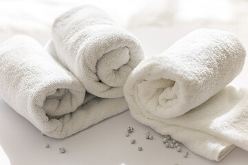 Close-up of a rolled white bath towels on a white background.