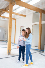 Fototapeta premium Brother and sister are on the construction site of their new room loft apartment with tablet and check the progress and enjoy and doing webconference or selfie
