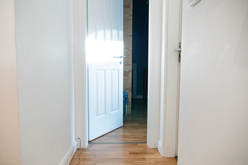 Open room door in house hallway with hardwood floor.