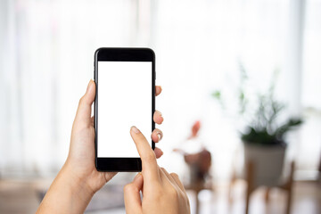 Close up view of woman hands using smart phone with modern office blurred background. Blank screen monitor for graphic display montage.