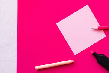 top view of stationery near blank paper note on textured white and pink.