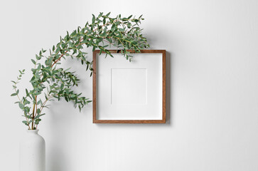 Square frame mockup for artwork, quote or print presentation on white wall with fresh eucalyptus plant in vase