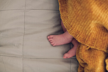 Gentle puffy baby legs on a linen bedspread, top view